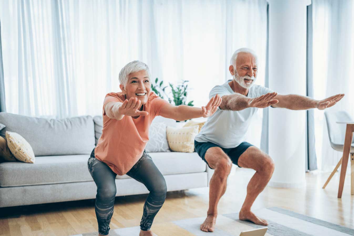 old healthy couple balancing and stretching in the living room
