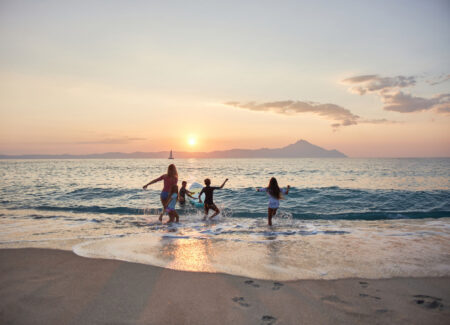 Family playing in ocean waves at sunset on beach