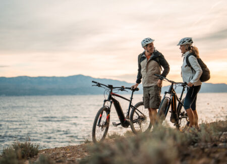 Active Senior Couple with Electric Bikes at Sea at Dawn
